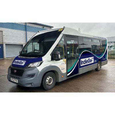 IndieGo branded minibus parked in an industrial area, featuring a white, blue, and green design with registration plate SF21 CYA.