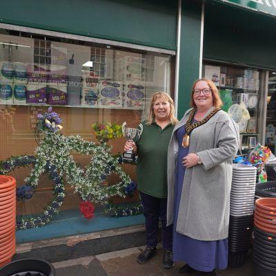 Mayor presenting trophy to wining shop owner for cycle themed window display