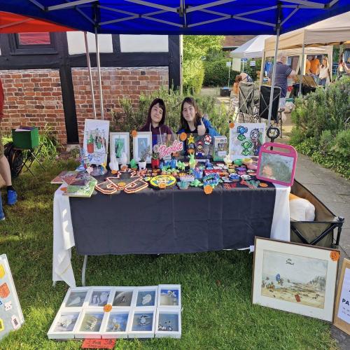 Two teenagers sat at a colourful market stall showcasing their creations